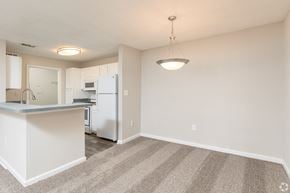 Acworth apartment for rent - an empty living room with a kitchen with a white refrigerator and a counter top