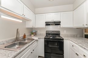 High Point apartment for rent - A kitchen with a black stove top oven and a stainless steel sink.