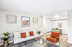 Shawnee Mission apartment for rent - A living room with a white couch, a black and white patterned rug, and a red chair.