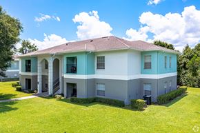 Lakeland apartment for rent - a white and blue house with a green lawn and trees at Waters Edge Apartments, Lakeland