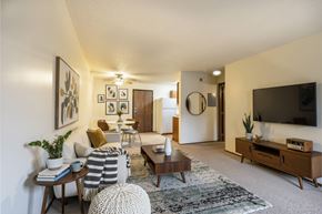 Altoona apartment for rent - A living room with a grey and white striped ottoman in front of a wooden coffee table.