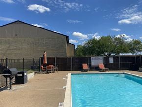 College Station apartment for rent - A pool area with a black fence and a building in the background.