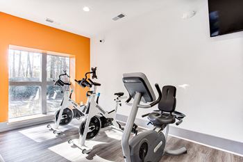 A home gym with orange walls and a television mounted on the wall