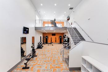 A gym with orange tiles on the floor and a staircase