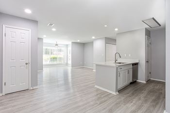 An empty kitchen and living room with a door to a window