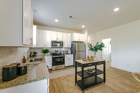 Hoschton apartment for rent - A kitchen with white cabinets and a granite countertop.