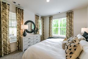 Hoschton apartment for rent - A bedroom with a large bed, a dresser with a mirror, and patterned curtains.