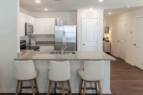 Kingsport townhouse for rent - a kitchen with an island with three chairs and a stainless steel refrigerator