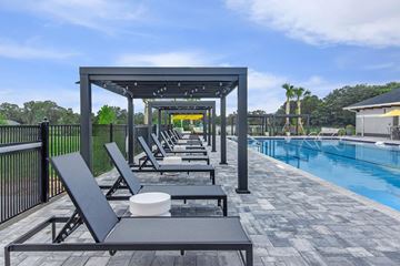Ocala apartment for rent - A poolside area with lounge chairs and a table.