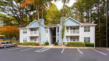 A parking lot in front of a two-story apartment building