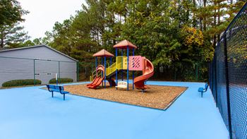 A playground with a blue surface and a red slide