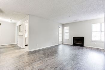 A large, empty room with a fireplace and wood flooring