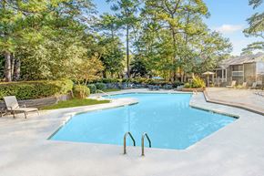 Columbia apartment for rent - A large blue swimming pool surrounded by trees and a wooden deck. at Grove at St. Andrews, Columbia, SC