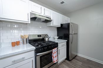 A kitchen with white cabinets and stainless steel appliances and a black refrigerator