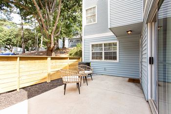 A patio with two chairs and a wood fence