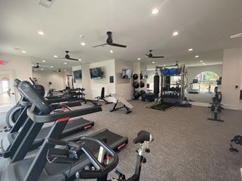 A spacious fitness room with cardio equipment and a flat screen tv