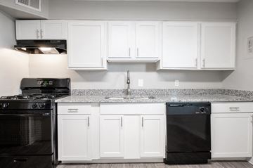 Columbus apartment for rent - A black stove and dishwasher in a kitchen with white cabinets.