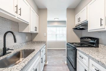 Indianapolis apartment for rent - A kitchen with white cabinets and a black and white tiled backsplash.
