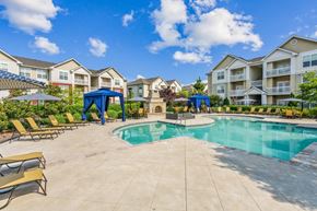 Suffolk apartment for rent - A swimming pool surrounded by lounge chairs and umbrellas in a residential area.at Century Hampton Roads, Virginia