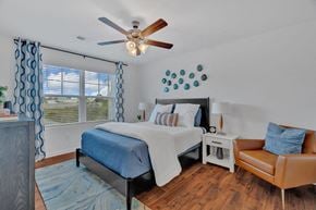 Gray apartment for rent - A bedroom with a bed, chair, and ceiling fan.