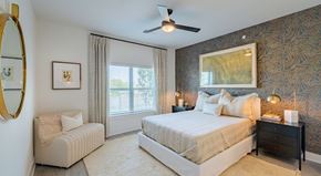 Frisco apartment for rent - A bedroom with a large bed, a chair, and a ceiling fan.