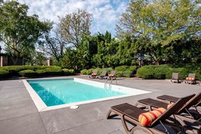 Prairie Village apartment for rent - A pool surrounded by trees and lounge chairs.