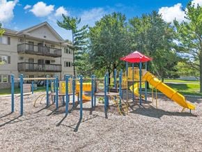 West Des Moines apartment for rent - A playground with a yellow slide and a red roofed structure.