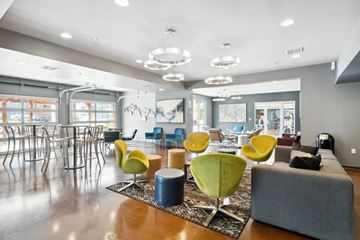 Roanoke apartment for rent - A modern living room with a grey sofa, yellow chairs and a wooden floor.