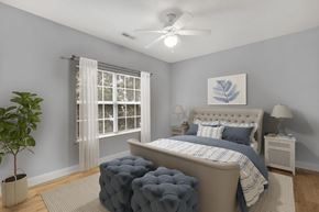 Moncks Corner apartment for rent - A bedroom with a large bed, a ceiling fan, and a potted plant.