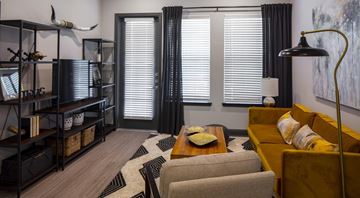 Fort Worth apartment for rent - A living room with a yellow couch and a black bookshelf.
