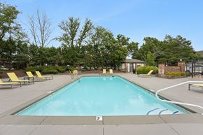 Prairie Village apartment for rent - A large outdoor swimming pool surrounded by trees and lounge chairs.
