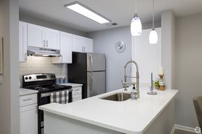 Doraville apartment for rent - A kitchen with a black refrigerator and white cabinets.