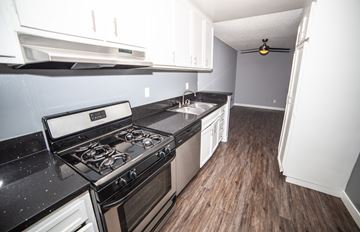 Sherman Oaks apartment for rent - a kitchen with white cabinets and black counter tops and a stove top oven
