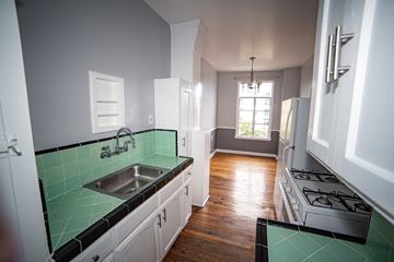 Los Angeles apartment for rent - A kitchen with white cabinets and a green tile backsplash.