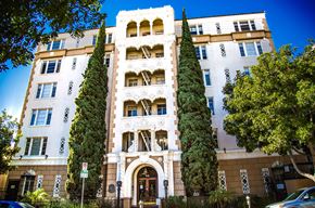 Los Angeles apartment for rent - A tall building with a large arched doorway and balconies on the upper floors.