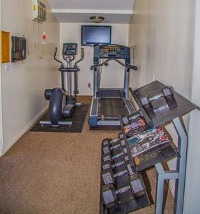 Encino apartment for rent - a room with a treadmill and a table with a television on the wall