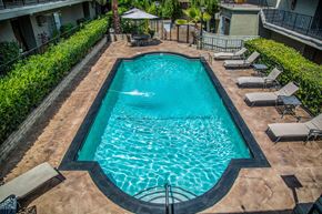 Encino apartment for rent - a swimming pool with lounge chairs and umbrellas in front of a building