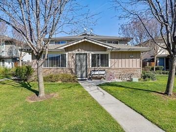 San Jose condo for rent - A house with a brown roof and a white fence is surrounded by a grassy lawn and trees.