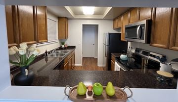 Morgan Hill triplex for rent - A kitchen with wooden cabinets and a tray of green and yellow apples.