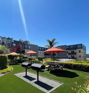 San Bruno apartment for rent - a park with picnic tables and umbrellas in front of an apartment building