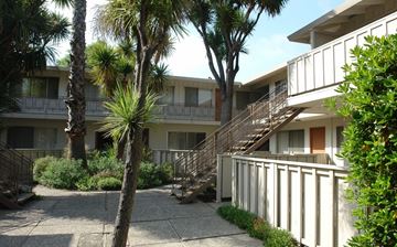 San Jose apartment for rent - a building with stairs and palm trees in front of it