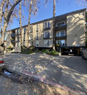 San Jose apartment for rent - an apartment building with a gravel parking lot and trees