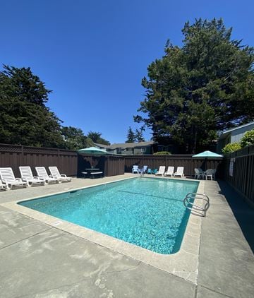 Santa Cruz apartment for rent - a pool with white chairs and umbrellas and a blue sky
