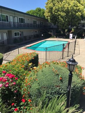 San Jose apartment for rent - Colonial House Apartments San Jose a pool with a fence and flowers in front of a building