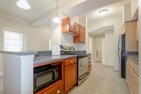 Cleveland apartment for rent - Kitchen area of an apartment fitted with stainless steel appliances, spacious cabinets, and tiled flooring at Park Lane Villa.