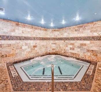 A hot tub in a room with stone walls.