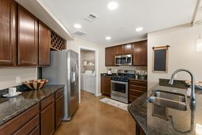 Austin apartment for rent - A kitchen with brown cabinets and a black counter top. at Bridge at Heritage Woods, Austin, Texas