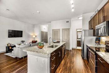 A modern kitchen with wooden floors and stainless steel appliances.