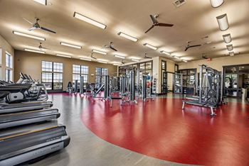 A gym with a red floor and various exercise equipment.