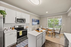 Austin townhouse for rent - A kitchen with white cabinets and a black stove top oven. at Bridge at Canyon Creek, Austin, Texas